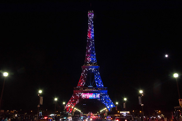 Red and blue lights and a welcoming message that reads in French "Neymar Jr." adorn the Eiffel Tower to celebrate the arrival of Brazilian footballer Neymar to Paris on August 5, 2017 after his signing with the Paris Saint-Germain (PSG) football club. Paris Saint-Germain football club celebrated the arrival of the Brazilian superstar to the French capital following his 222-million-euro ($264m) transfer from Barcelona. / AFP PHOTO / OLIVIER MORIN