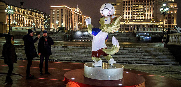 Passers-by take pictures of a figure of Zabivaka, the official mascot for the 2018 FIFA World Cup, at Manezhnaya square in downtown Moscow on November 29, 2017. / AFP PHOTO / Mladen ANTONOV