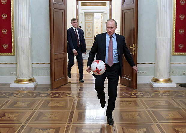 (FILES) This file photo taken on November 25, 2016 shows Russian President Vladimir Putin playing with an official match ball for the 2017 FIFA Confederations Cup, named "Krasava", after a meeting with FIFA president at the Kremlin in Moscow. Russia is gearing up to host the World Cup for the first time while facing the herculean task of eradicating racism and hooliganism and warding off the threat of a terror attack. / AFP PHOTO / SPUTNIK / Alexey DRUZHININ