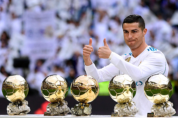Real Madrid's Portuguese forward Cristiano Ronaldo poses with his five Ballon d'Or trophies ahead of the Spanish league football match between Real Madrid and Sevilla at the Santiago Bernabeu Stadium in Madrid on December 9, 2017. / AFP PHOTO / PIERRE-PHILIPPE MARCOU