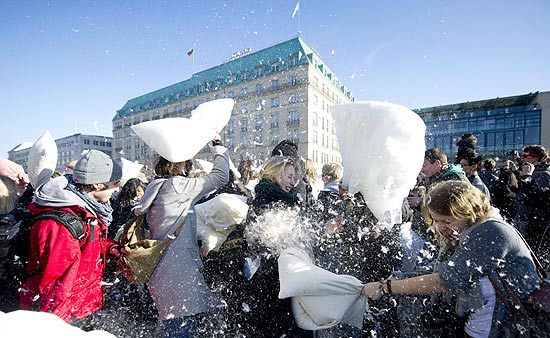 ORG XMIT: EIS023 People participating in a mass pillow fight "flashmob" event throw pillows at each other in front of the Brandenburger Gate in Berlin on March 20, 2011. AFP PHOTO / JOHANNES EISELE