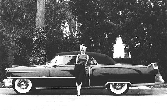 A atriz Marilyn Monroe posa com seu Cadillac 