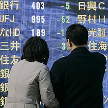 Casal japonês olha indicadores eletrônicos em Tóquio; internet une os parceiros