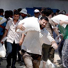 Palestinos recolhem sacos de alimentos no centro de distribuição da ONU, em Gaza