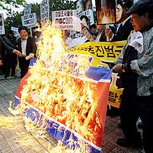 Ativistas queimam bandeira em protesto ao encontro de representantes norte-coreanos