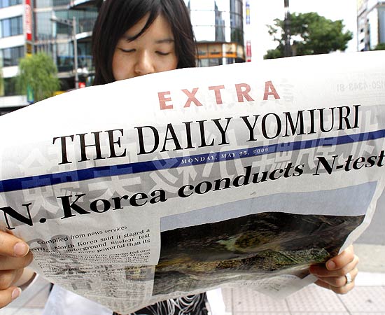 Garota japonesa lê edição extra de jornal que informa sobre o teste nuclear norte-coreano