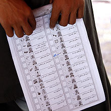 Homem mostra cdula de votao distribuda em comcio para ensinar afegos a votar