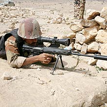 Soldado armado em posio de ataque durante uma operao militar