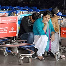 Passageiros descansam sobre carrinhos de bagagem em meio  greve dos pilotos