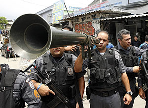 Policiais militares exibem bazuca do Exército encontrada em uma casa no Complexo do Alemão, na zona norte do Rio