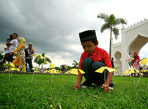 Menino indonsio coloca flores de papel na terra, para marcar sexto aniversrio de terremoto e tsunami em Banda Aceh