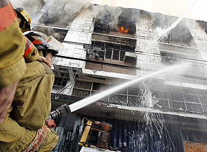 Bombeiro utiliza mangueira para apagar chamas que atingem prdio do sindicato dos funcionrios do setor areo, nas Filipinas