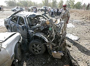 Policiais inspecionam carro usado em explosão de bomba no estacionamento de petroleira iraquiana; ataques mataram 45