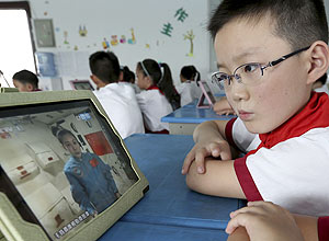 Estudante assiste  aula dos astronautas chineses Nie Haisheng, Zhang Xiaoguang e Wang Yaping em seu iPad