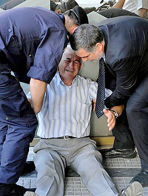 TOPSHOTS An crying elderly man is assisted by an employee and a policeman outside a national bank branch as pensioners queue to get their pensions, with a limit of 120 euros, in Thessaloniki on 3 July, 2015. Greece is almost evenly split over a crucial weekend referendum that could decide its financial fate, with a 'Yes' result possibly ahead by a whisker, the latest survey Friday showed. Prime Minister Alexis Tsipras's government is asking Greece's voters to vote 'No' to a technically phrased question asking if they are willing to accept more tough austerity conditions from international creditors in exchange for bailout funds. AFP PHOTO /Sakis Mitrolidis ORG XMIT: THESS438