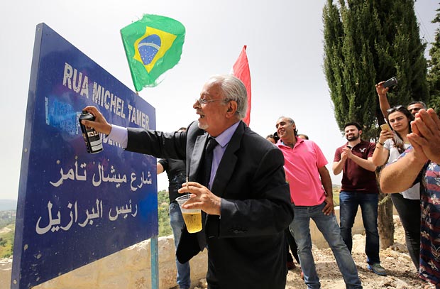 A Lebanese man uses a spray to erase the word "vice" from a plaque reading in Portuguese and Arabic: "Street Michel Temer, Vice President of Brasil" at the entrance of the village of Btaaboura, north of Beirut, on May 13, 2016 during a celebration after Brazilian of Lebanese descendent Michel Temer became acting President of Brazil. Temer, the current acting president of Brasil is the son of Maronite Lebanese parents, and visited Btaaboura where his father grew up twice in 1997 and 2011. / AFP PHOTO / IBRAHIM CHALHOUB