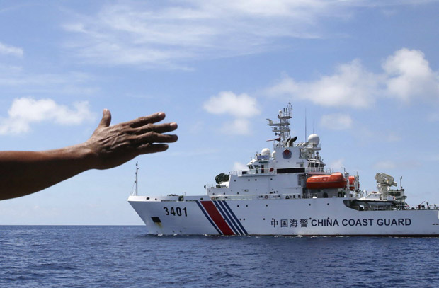 Tripulante de barco filipino sinaliza para navio da Marinha da China