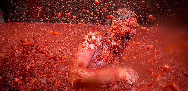 Homem joga polpa de tomate durante o festival anual 