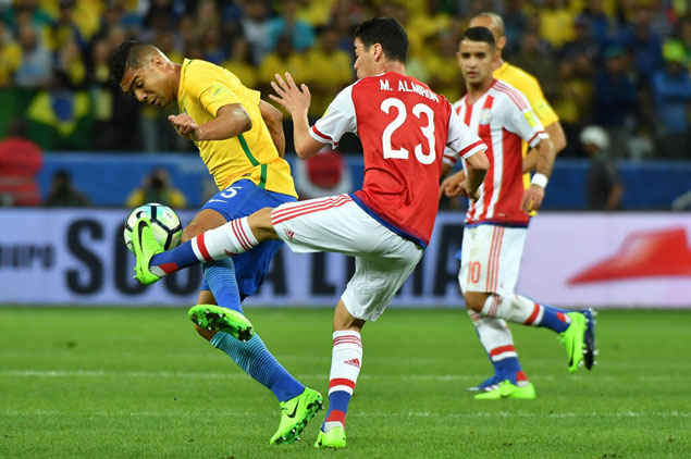 O volante Casemiro, do Brasil, disputa a bola com o paraguaio Almiron em partida das eliminatrias