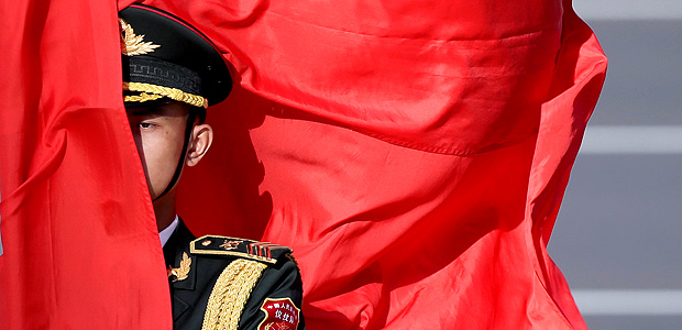 Soldado chins parcialmente encoberto por bandeira vermelha