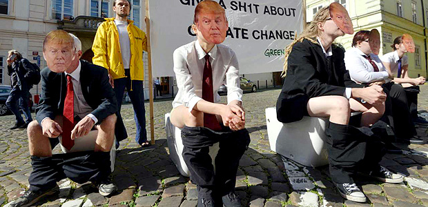 Activists of environmental group Greenpeace wear the mask of US President Donald Trump while sitting on toilets in front of a banner reading "give a shit about climate change" as they stage a protest against US President Donald Trump's decision to pull out of the 195-nation Paris climate accord deal on June 05, 2017 in front of the US Embassy in Prague. / AFP PHOTO / Michal Cizek
