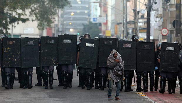 A drug user walks in front of riot police during a police operation in a neighborhood known to locals as Cracolandia (Crackland), in downtown Sao Paulo, Brazil 