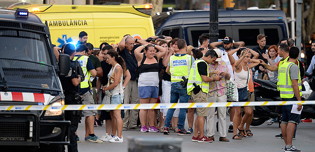 Policemen check the identity of people standing with their hands up after a van ploughed into the crowd, killing two persons and injuring several others on the Rambla in Barcelona on August 17, 2017. A driver deliberately rammed a van into a crowd on Barcelona's most popular street on August 17, 2017 killing at least two people before fleeing to a nearby bar, police said. Officers in Spain's second-largest city said the ramming on Las Ramblas was a "terrorist attack" and a police source said one suspect had left the scene and was "holed up in a bar". The police source said they were hunting for a total of two suspects. / AFP PHOTO / Josep LAGO