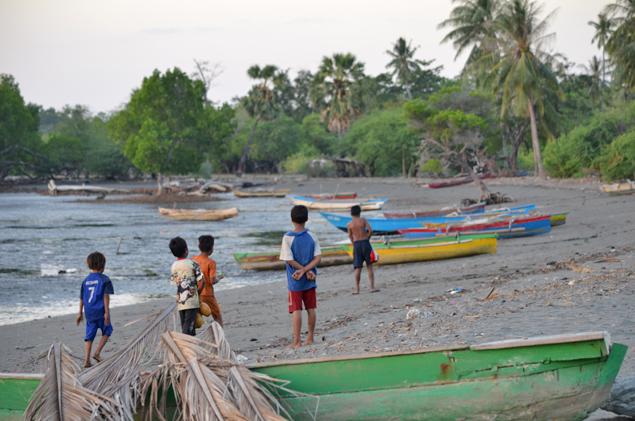 Crianas brincam entre os barcos de pescadores na praia de Metinaro, em Timor-Leste 