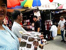 Mulher vende bolsas falsificadas em Shangai; uma indstria que movimenta US$ 500 bilhes