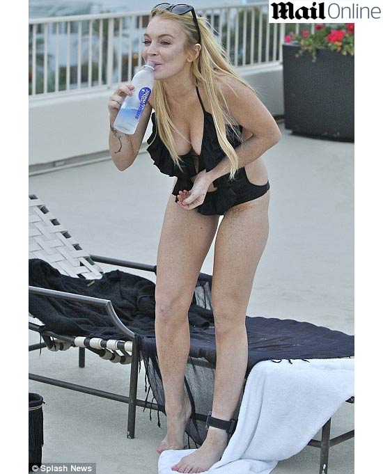 Lindsay Lohan forgets about covering up her SCRAM anklet to go sunbathing in sexy black swimsuit