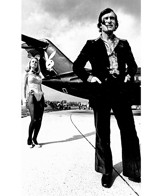 Hugh Hefner  frente de seu jato e de uma coelhinha da "Playboy"