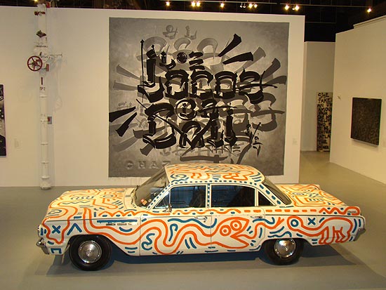 Carro pintado por Keith Haring, em frente à tela de Chaz Bojórquez.