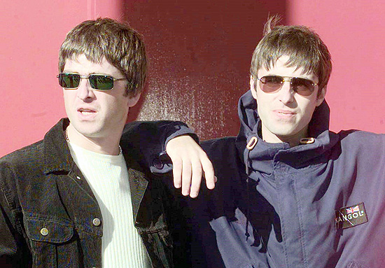 Os irmãos Liam [dir.] e Noel Gallagher, integrantes do conjunto musical Oasis, durante entrevista em Exeter, Inglaterra: Liam Gallagher [R] and his songwriting brother Noel walk out of the concert hall for a photo-opportunity prior to the first date on their 1997 UK tour, September 13. Oasis's new record has gone straight to number one in the UK charts. rus/DIGITAL/Photo by Russell Boyce