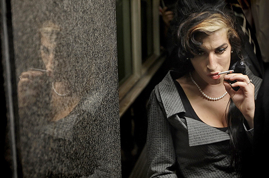 Amy Winehouse fuma um cigarro no intervalo de audiência no Tribunal de Westminster, em Londres, em julho de 2009