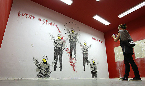 Mulher tira foto de mural perdido de Banksy que foi redescoberto em Berlim