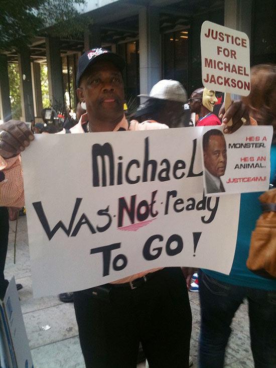 Bristol Clayton segura cartazes com os dizeres "Michael não estava pronto para ir embora" diante do tribunal
