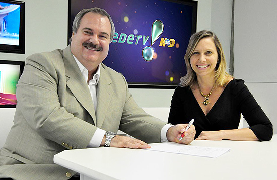 Gilberto Barros assina contrato com a RedeTV! ao lado da superintendente Artística da emissora, Mônica Pimentel 