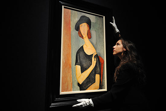 Mulher segura o quadro "Jeanne Hebuterne (de chapu)", de Amedeo Modigliani
