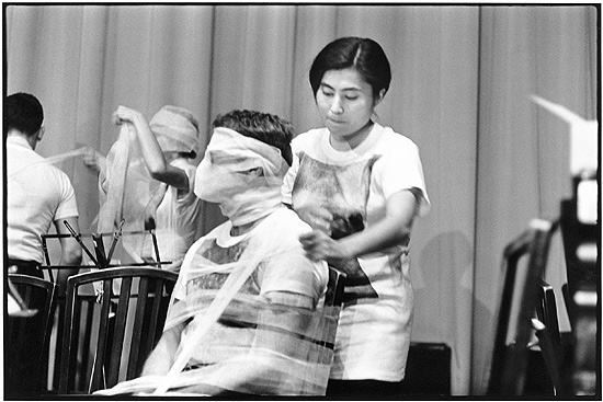 Yoko Ono na performance "Sky Piece to Jesus Christ", em que pessoas eram amarradas juntas, em 1965