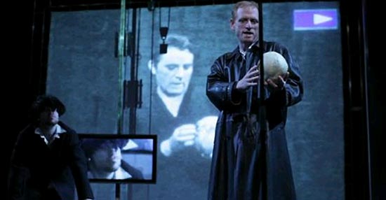 O ator Scott Shepherd reproduz no palco gestual de Richard Burton na montagem filmada de "Hamlet", ao fundo