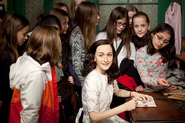 Estudantes cercam a figura de cera de Anne Frank sentada diante de uma escrivaninha no Museu Madame Tussauds, em Berlim, na Alemanha