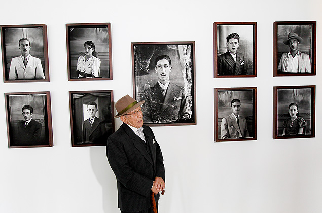 O fotgrafo Assis Horta, 95, posa em frente em frente aos retratos de exposio sobre a CLT, em Braslia 