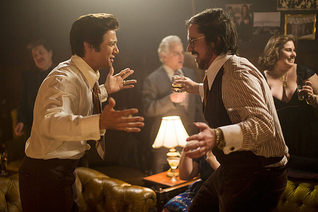Jeremy Renner (esq.), como Carmine Polito e Christian Bale, como Irving Rosenfeld, em cena de 'Trapaa