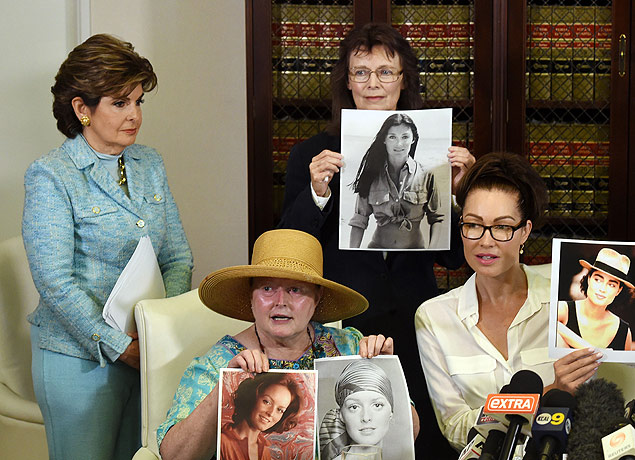 Attorney Gloria Allred (backgound L) watches as three alleged sexual assault victims of comedian Bill Cosby (L-R) Colleen Hughes, Linda Ridgeway Whitedeer and actress Eden Tirl hold up younger photos of themelves during a news conference in Los Angeles, California on August 12, 2015. Cosby, a pioneering African-American comedian who played a beloved family doctor on the hit 1980s sitcom 