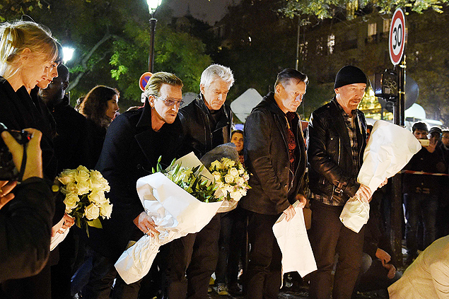 Irish band U2 (From L) lead singer Bono, bass player Adam Clayton, drummer Larry Mullen Jr and guitarist The Edge pay homage to attacks' victims near the Bataclan concert hall on November 14, 2015 in Paris, a day after a series of coordinated attacks in and around Paris. Islamic State jihadists claimed a series of coordinated attacks by gunmen and suicide bombers in Paris that killed at least 129 people in scenes of carnage at a concert hall, restaurants and the national stadium. U2 has canceled two sold-out concerts in Paris, including one to be broadcast live on November 14, and Foo Fighters cut short their tour after attacks that killed at least129 people. AFP PHOTO / FRANCK FIFE ORG XMIT: 10575