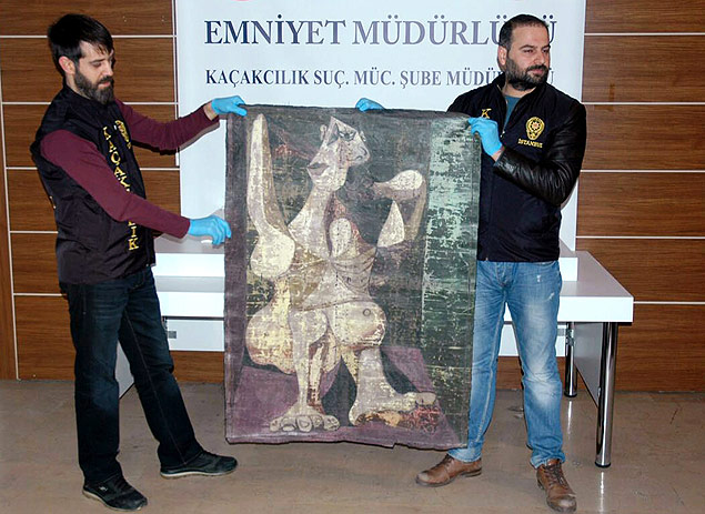 Turkish police from the Istanbul Police Department Anti-Smuggling and Organized Crime Unit, hold-up an original painting by Spanish artist Pablo Picasso, "Woman Dressing Her Hair", on January 30, 2016, in Istanbul. Turkish police have recovered an original painting by Picasso in an undercover operation in Istanbul, the state-run Anatolia news agency reported. The operation targeted alleged art thieves attempting to sell the painting "Woman Dressing Her Hair" which was stolen from a collector in New York, Anatolia said. / AFP / STR / RESTRICTED TO EDITORIAL USE - MANDATORY MENTION OF THE ARTIST UPON PUBLICATION - TO ILLUSTRATE THE EVENT AS SPECIFIED IN THE CAPTION ORG XMIT: 4990