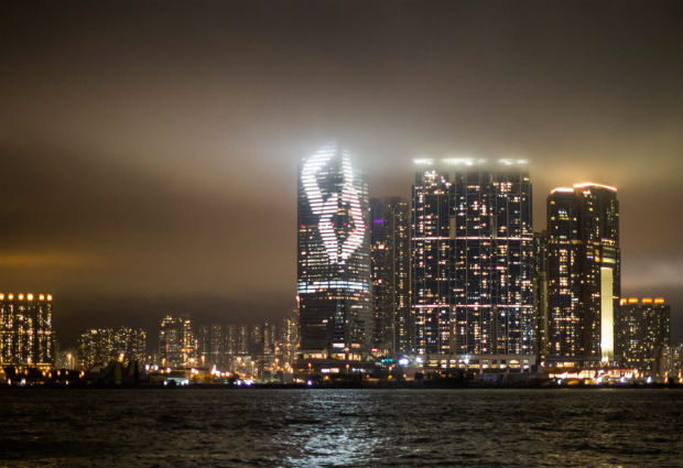 Japanese artist Tatsuo Miyajima's light installation for Art Basel Hong Kong entitled 'Time waterfall' is projected onto the facade of the International Commerce Centre (ICC) (centre) on the Kowloon waterfront on March 21, 2016, as low lying clouds cover the upper half of the 490-metre-high building. / AFP PHOTO / ANTHONY WALLACE ORG XMIT: ACW101