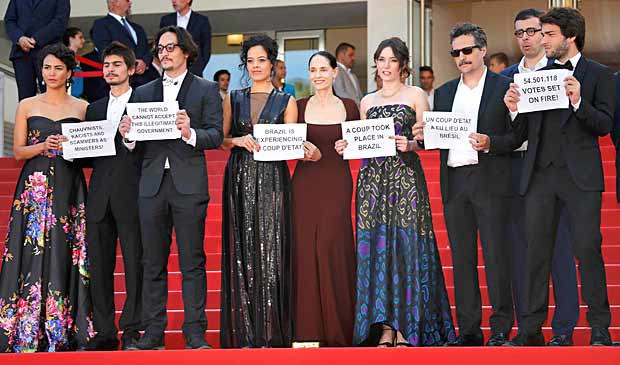 Director Kleber Mendonca Filho (3rdR) and cast members Maeve Jinkings (4thL), Sonia Braga (C), Barbara Colen (L), producer Emilie Lesclaux (4thR) and team hold placards to protest against the impeachment of suspended Brazilian President Dilma Rousseff on the red carpet as they arrive for the screening of the film "Aquarius" in competition at the 69th Cannes Film Festival in Cannes, France, May 17, 2016. REUTERS/Jean-Paul Pelissier ORG XMIT: JPP4
