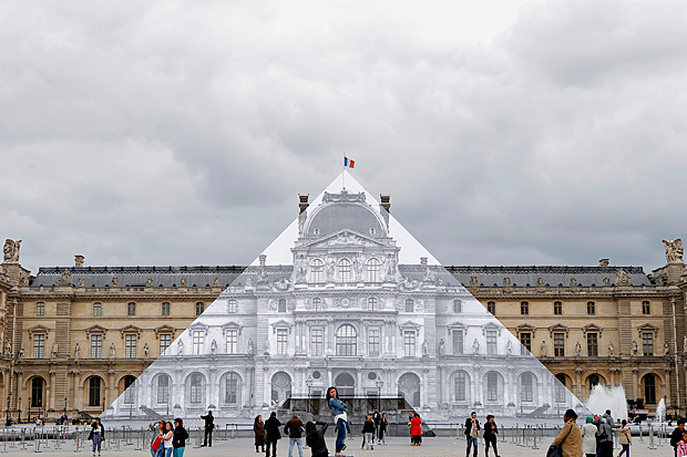 Turistas andam em torno do museu do Louvre, que exibe fotografia do artista JR