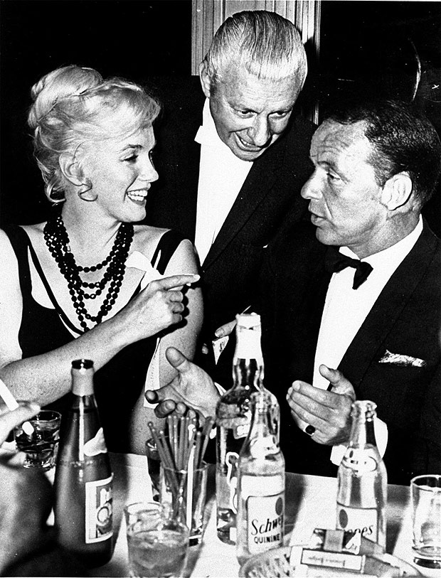 Marilyn com Frank Sinatra ( dir.) e homem no identificado em festa do filme 'Can Can', em 1960